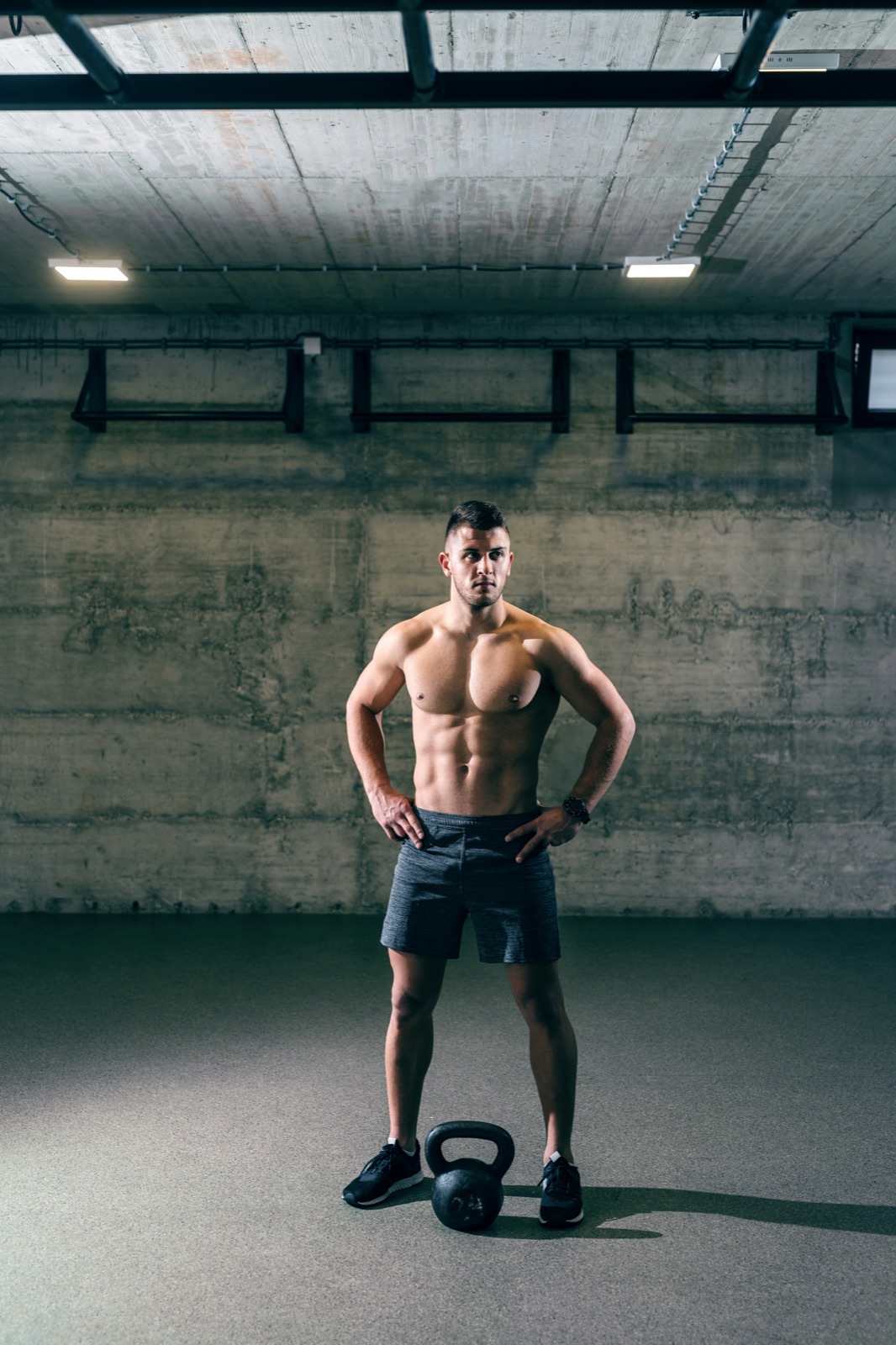 Trainer standing over a kettlebell in a concrete gym
